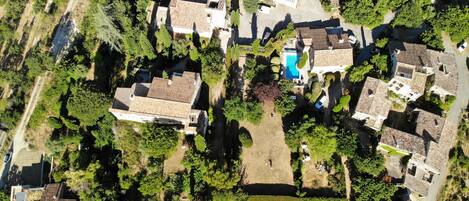 An aerial view of a residential area with multiple houses, a swimming pool, and well-maintained gardens.