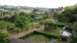 Un jardin avec un bassin, des haies taillées avec soin et des plantes en pot.