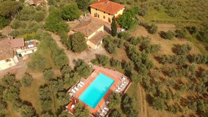 Vue aérienne d’une propriété comprenant une piscine, une grande maison et un espace verdoyant.