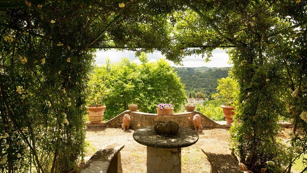 Un jardin agrémenté d’une fontaine en pierre, de pots en terre cuite et d’un banc.