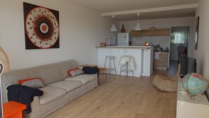 A modern living room with a sofa, a small coffee table, and a kitchen area with a fridge, microwave, and bar stools. - Seaview Apartment with a lovely harbour view, terrace and parking (Antibes)
