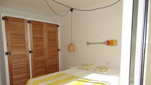 A bedroom with a bed, two pillows, a hanging lamp, and a wooden wardrobe. - Seaview Apartment with a lovely harbour view, terrace and parking (Antibes)