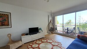 A modern living room with a flat-screen TV, a hanging chair, and a large window offering a view of the outdoors. - Seaview Apartment with a lovely harbour view, terrace and parking (Antibes)