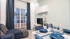 A modern living room with a sofa, dining table set for four, and a TV. - DB Nice Apartment Sagrada Familia (Barcelona)