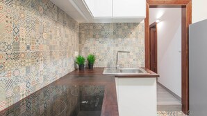 A kitchen with patterned tiles, a sink, and two potted plants. - DB Nice Apartment Sagrada Familia (Barcelona)