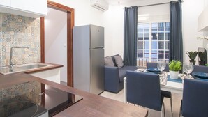 A compact kitchen with a sink, a refrigerator, and a dining area with a table set for two. - DB Nice Apartment Sagrada Familia (Barcelona)
