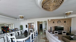 A modern living room with a dining area, a chandelier, a TV, and a fireplace. - Amazing Nile View & Pyramids (Cairo)