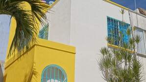 A building with a yellow facade, a blue door, and a window with blue bars.