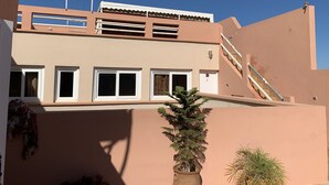 Un edificio con techo plano, varias ventanas y una escalera que conduce a un nivel superior.