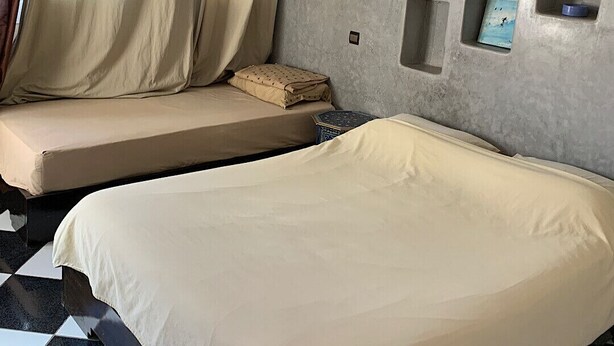 Una habitación de hotel con cama, un pequeño sofá y una ventana con cortinas.