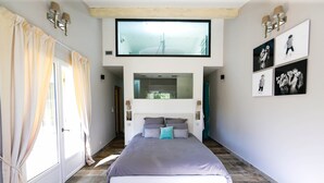 A bedroom with a bed, a TV, and a wall-mounted mirror.