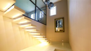 A modern staircase with integrated lighting, a large mirror, and a view of the outside.