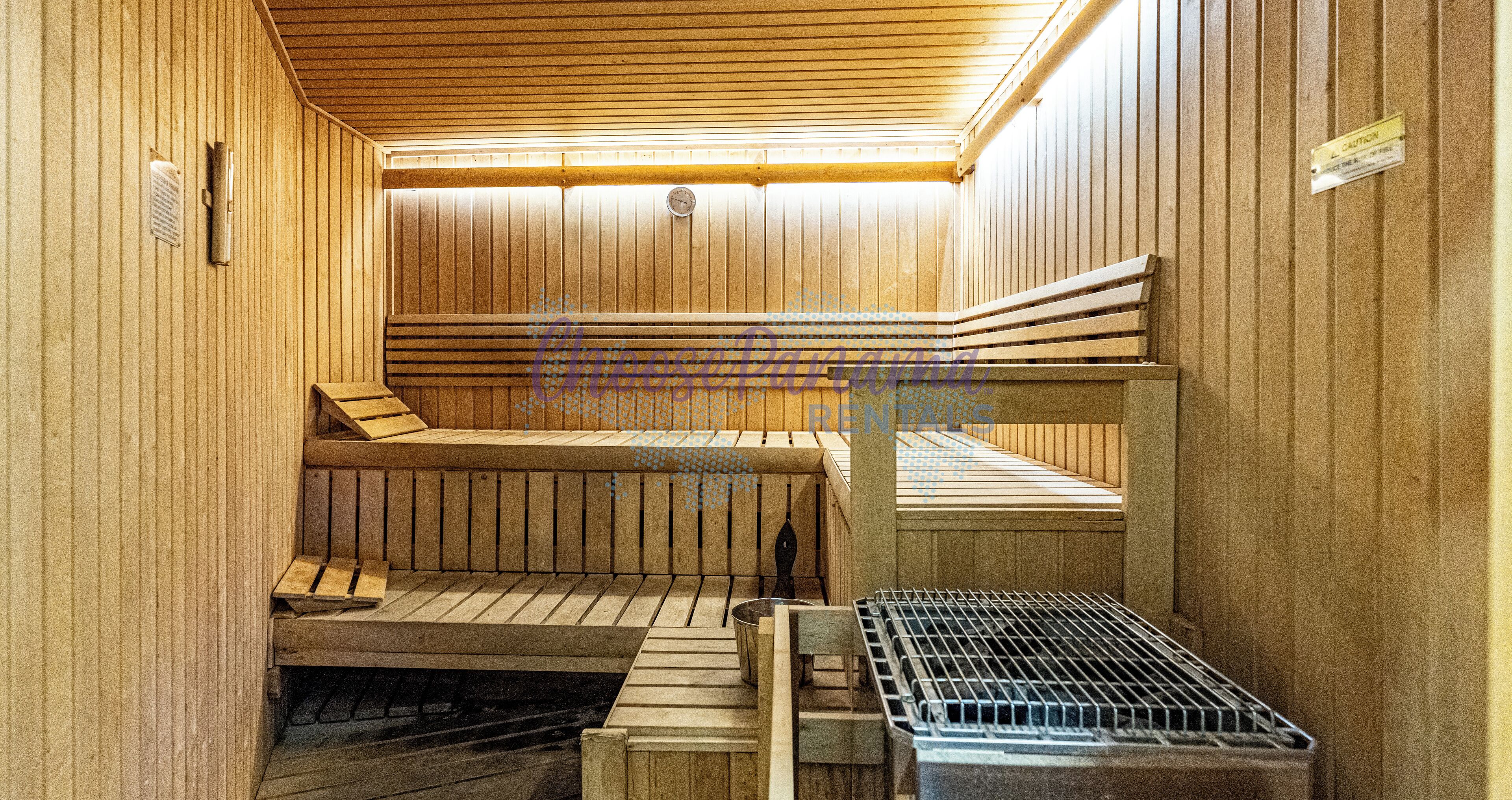 Un sauna avec des bancs en bois et une grille métallique.
