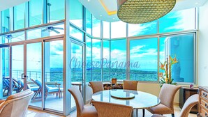 A modern interior with a round table and chairs, large windows, and a ceiling fan. - 24o Penthouse Unique Design 2 Balconies Oceanview (Panama City)