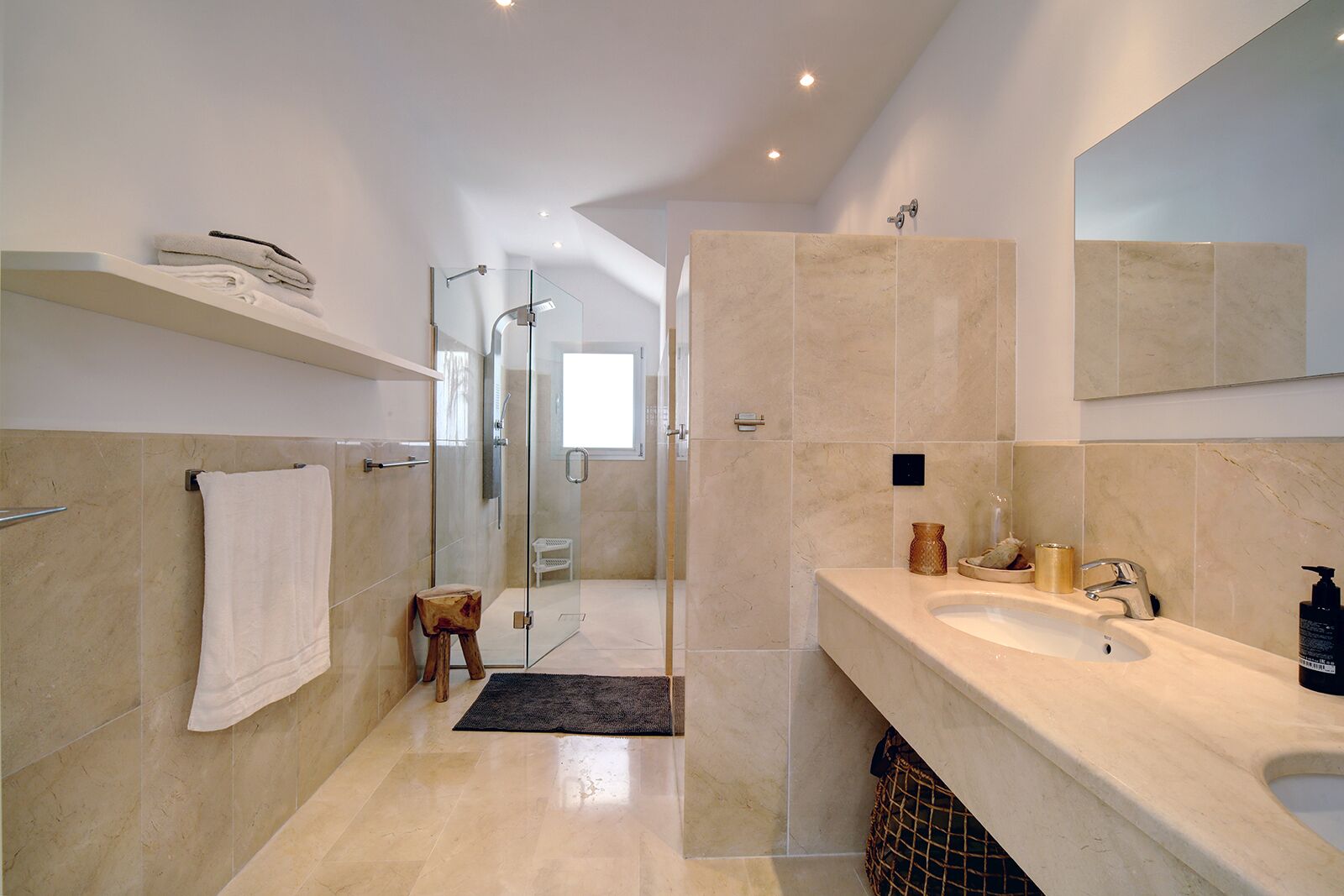 A modern bathroom with a large mirror, a sink, and a shower area.