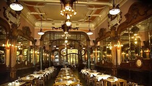 A grand dining hall with ornate chandeliers, multiple tables, and classical architectural details. - Home4you Downtown Porto (Porto)