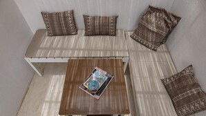 A small, cozy seating area with a bench and a table, both featuring patterned cushions. - Holiday house 200 meters from Laginha beach (Mindelo)