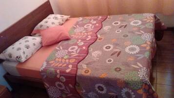 Un lit avec une couvre-lit à motifs floraux, un oreiller rose et un oreiller blanc à motifs.