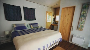 Ein Schlafzimmer mit einem Bett, einer Holztür, einem Wandheizkörper und einem kleinen Tisch mit einer Lampe.