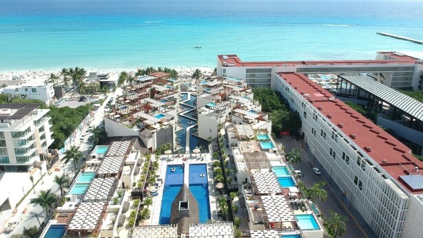 Un resort con varias piscinas, una playa y vista al océano.