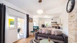 Een moderne woonkamer met een bank, een glazen salontafel en uitzicht op de keuken.
