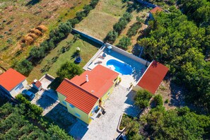 Vista aérea de una propiedad con piscina, varias construcciones y abundante vegetación.