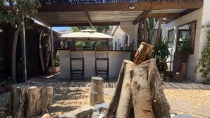 Eine Außenpatio-Terrasse mit einer Pergola, Holzstühlen und einem Tisch unter einem großen Sonnenschirm.
