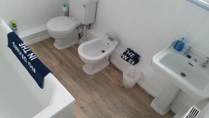 Een badkamer met toilet, hygiëneschuimer en wastafel.