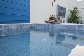 A swimming pool with clear blue water, surrounded by a tiled deck and a blue wall. - Villa Rodanthi in Kamilari (Kamilari)
