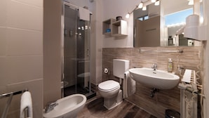 A modern bathroom with a glass-enclosed shower, a toilet, a bidet, and a sink. - Apartment in historical residence in the center of Finalborgo (Finale Ligure)