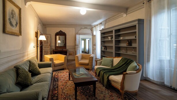 A traditional living room with a sofa, armchairs, a coffee table, and a patterned rug. - Apartment in historical residence in the center of Finalborgo (Finale Ligure)