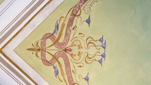 A close-up of a decorative ceiling with intricate patterns and a large, ornate letter. - Apartment in historical residence in the center of Finalborgo (Finale Ligure)