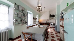 A kitchen with a dining table, chairs, and various kitchen utensils on the wall. - Apartment in historical residence in the center of Finalborgo (Finale Ligure)
