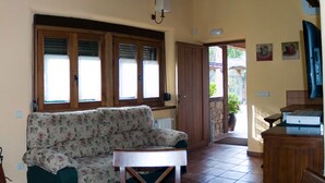 Una sala de estar con un sofá floral, armarios de madera y una mesita.