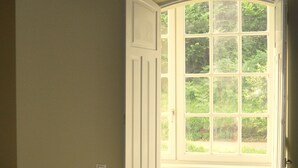 A bedroom with a bed, a window, and a door.