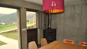 A dining area with a wooden table and chairs, a view of a stone bridge, and a large window.