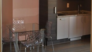 A modern kitchen with built-in appliances, a dining area with clear glass chairs, and wooden ceiling beams.