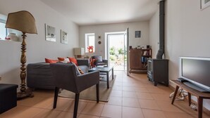 A modern living room with a sofa, armchair, and coffee table, a television, and a fireplace. - Casa do Olival, Guest accommodation in Figueiró dos Vinhos. (Figueiró dos Vinhos)