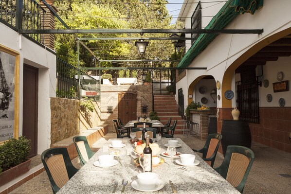 A dining area with a marble table set for a meal, surrounded by chairs, and a staircase leading to an upper level.