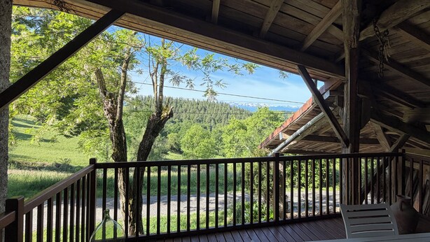 A wooden deck with a view of a forest and mountains.