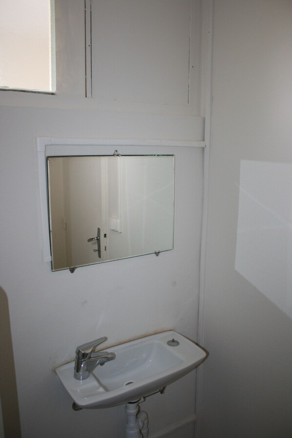Ein Badezimmer mit einem weißen Waschbecken, einem Spiegel und einem Fenster.