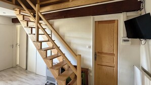 A wooden staircase in a room with a white door, a radiator, and a television mounted on the wall.