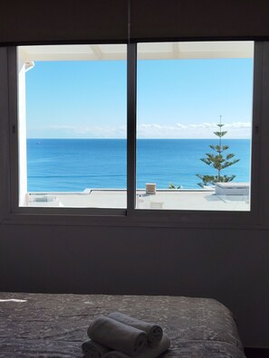 A room with a large window overlooking a clear blue sea and a small tree. - Modern & Sea views: Apartment La Roca (Torremolinos)