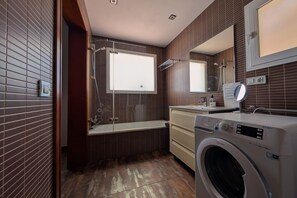 A modern bathroom with a built-in washing machine, a bathtub, and a large mirror. - Modern & Sea views: Apartment La Roca (Torremolinos)