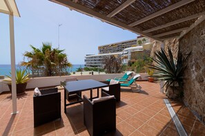 A terrace with a table and chairs, potted plants, and a view of the sea and a hotel in the background. - Modern & Sea views: Apartment La Roca (Torremolinos)