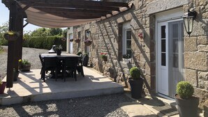 A stone building with a covered patio, outdoor seating, and potted plants. - SPACIOUS Family Farmhouse in 3 ACRES with STUNNING VIEWS, EXCLUSIVE USE. (Sourdeval)