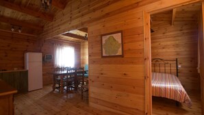 Une cabane en bois comprenant un coin repas, un lit et une carte accrochée au mur.
