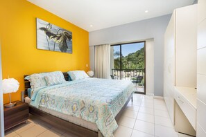 A bedroom with a large bed, a balcony with a view, and a painting on the wall.