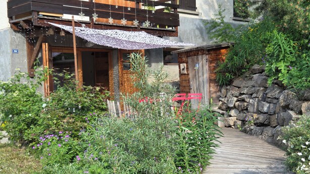 A wooden deck leading to a rustic cabin with a wooden porch and a stone wall. - Vars. Full-service center.  Private parking. Linens provided, beds made. (Vars)