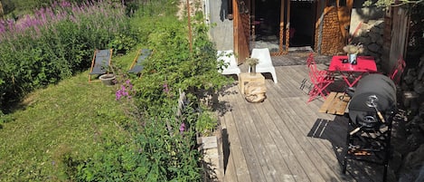 A wooden deck with outdoor seating, a barbecue grill, and a covered patio area.